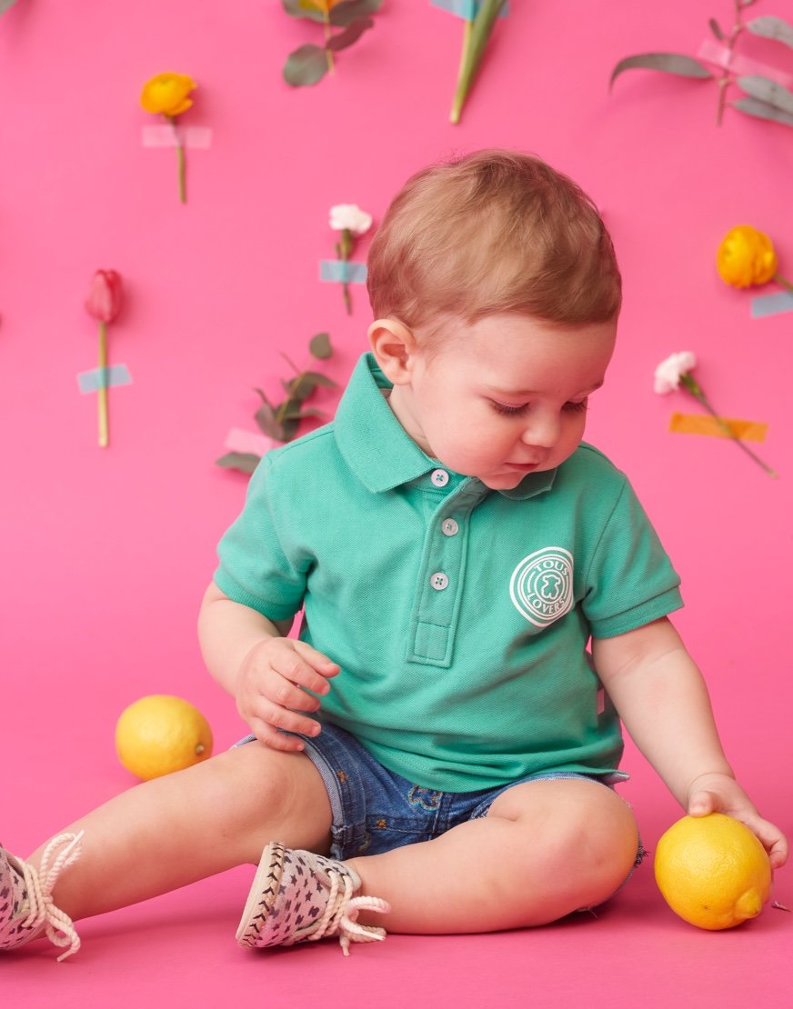 Niño jugando con un limón con fondo rosa